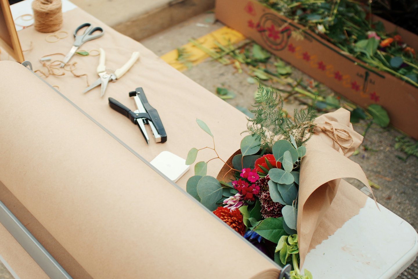 Blomsterhandlarens arbetsplats med verktyg, kraftpapper och en blomsterbukett.